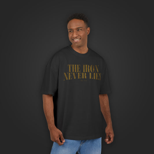 Mann trägt The Iron Never Lies Oversized Tee in Schwarz, Frontansicht mit goldenem Schriftzug